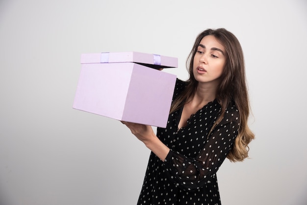 Молодая женщина смотрит на фиолетовую подарочную коробку