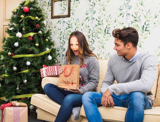 Young woman looking at shining gift bag