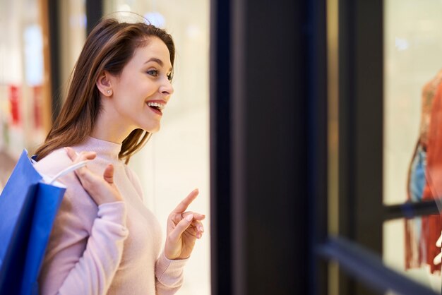 服を着てショーウィンドウを見ている若い女性