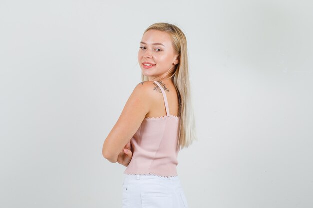 Young woman looking over shoulder and smiling in singlet