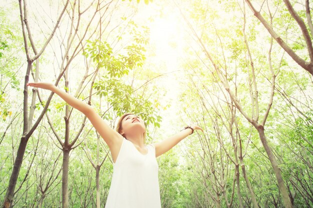 若い女性が木の背景に空を見て