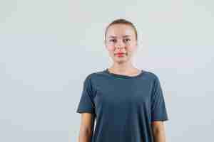 Foto gratuita giovane donna alla ricerca e sorridente in maglietta grigia