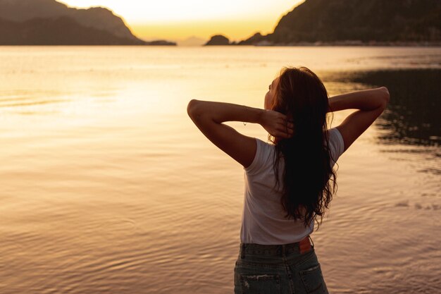 湖の岸に夕日を見て若い女性