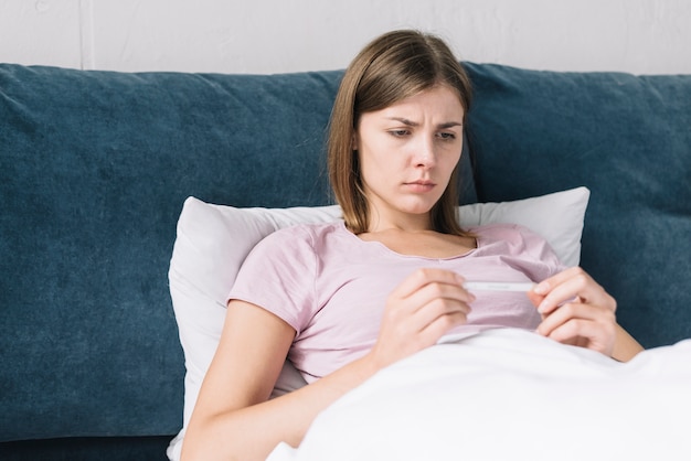 Free photo young woman looking at thermometer