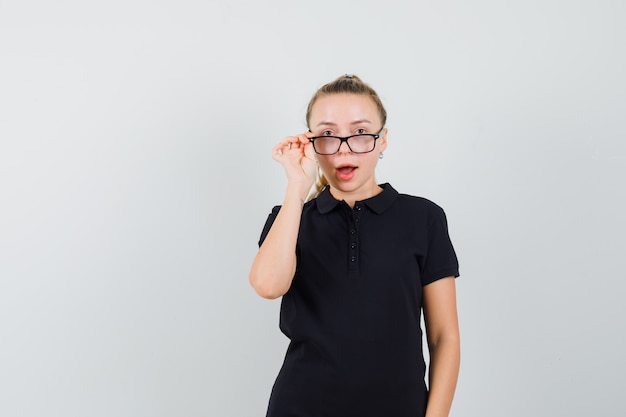 Молодая женщина смотрит через очки в черной футболке