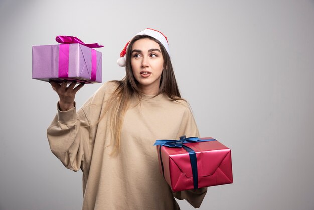 Foto gratuita giovane donna che esamina due scatole di regali di natale.