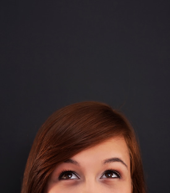 Free photo young woman looking up at blackboard