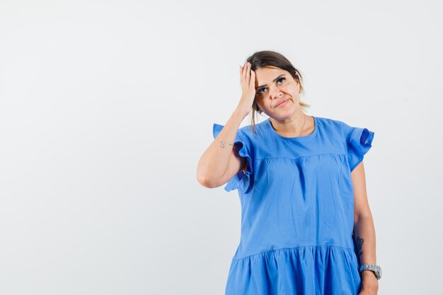 Young woman looking up in blue dress and looking pensive