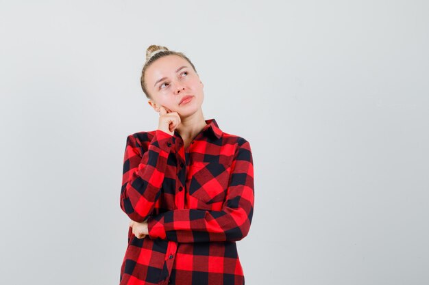 Young woman looking up in checked shirt and looking dreamy