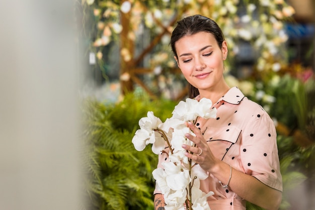 Foto gratuita giovane donna guardando fiori bianchi