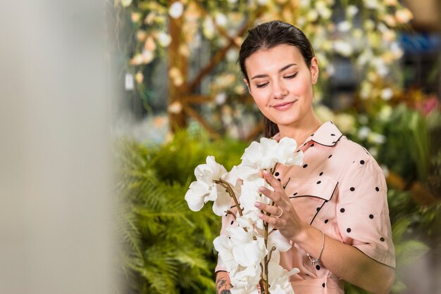 Молодая женщина смотрит на белые цветы