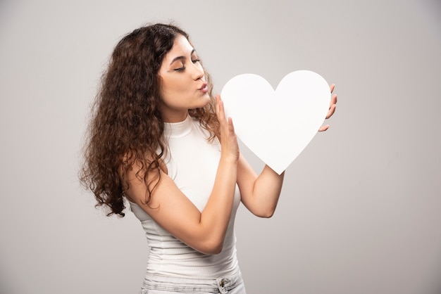 Young woman looking at white handmade paper heart. High quality photo