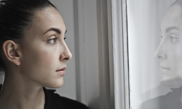 Молодая женщина смотрит в окно