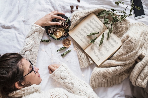 Молодая женщина, лежа на кровати с книгой