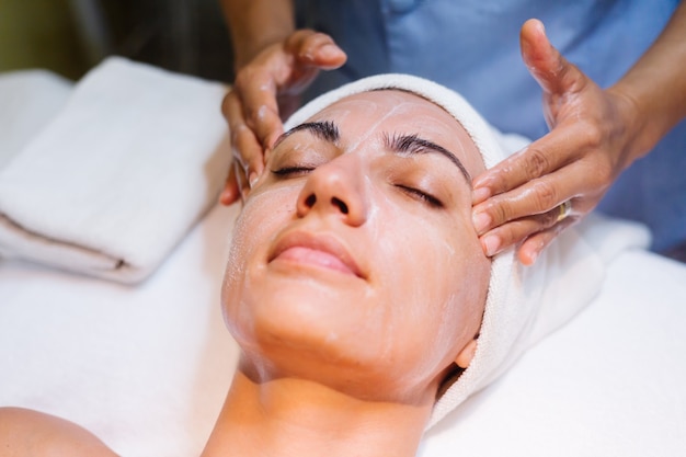 Young woman lying on cosmetologist's table during rejuvenation procedure.