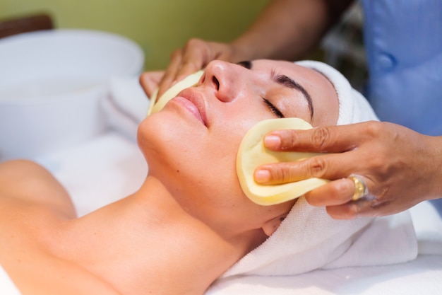 Young woman lying on cosmetologist's table during rejuvenation procedure.