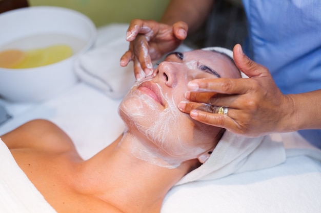 Young woman lying on cosmetologist's table during rejuvenation procedure.