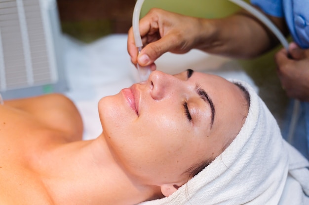 Young woman lying on cosmetologist's table during rejuvenation procedure