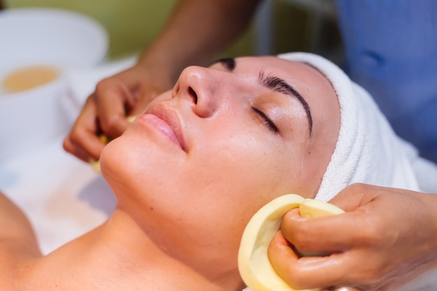 Young woman lying on cosmetologist's table during rejuvenation procedure.