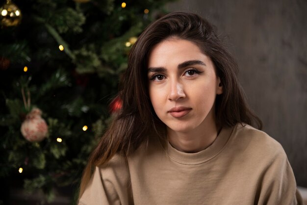 Young woman lying down on fluffy carpet near Christmas tree .