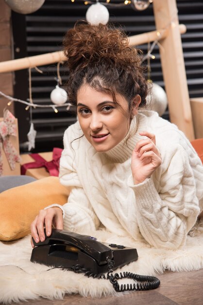 Young woman lying on fluffy carpet with telephone