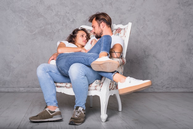 Foto gratuita giovane donna che si trova sull'uomo in poltrona