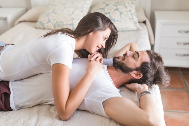 Young woman lying on man on bed