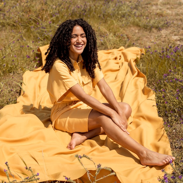 Бесплатное фото Молодая женщина, лежа на желтой ткани в природе