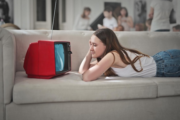 молодая женщина лежит на диване и смотрит телевизор