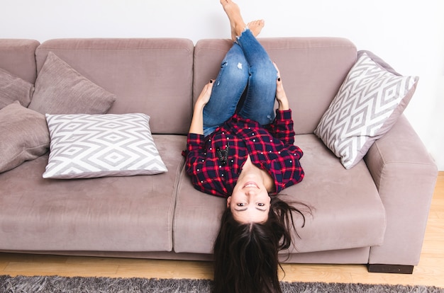 Foto gratuita giovane donna sdraiata sul divano con i suoi piedi a casa