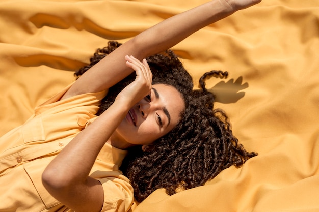 Молодая женщина, лежа на желтой ткани в природе