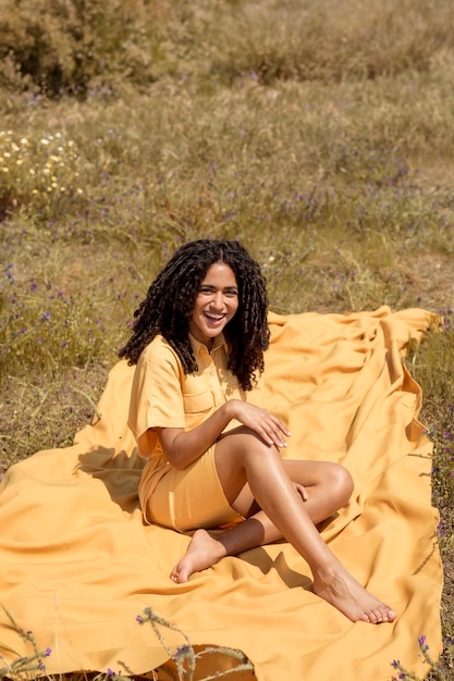 Free photo young woman lying on yellow cloth in nature