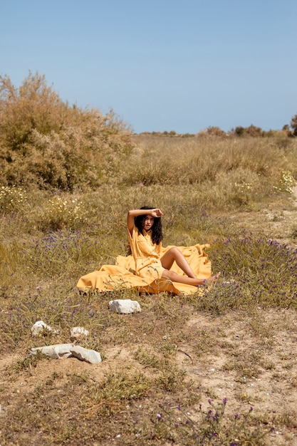 Free photo young woman lying on yellow cloth in nature