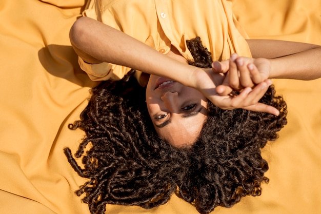 Free photo young woman lying on yellow cloth in nature