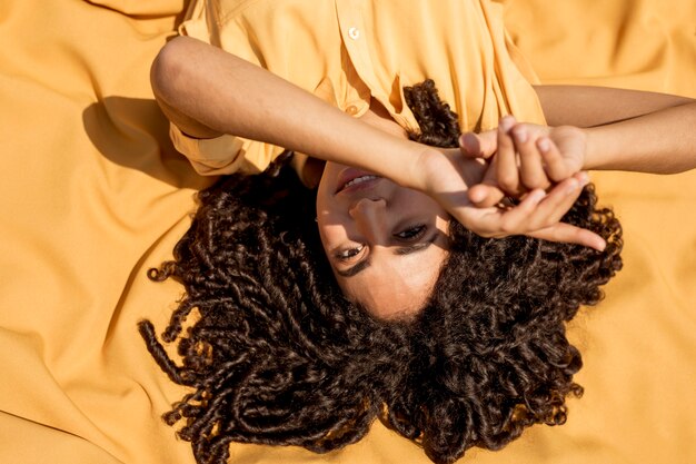 Young woman lying on yellow cloth in nature