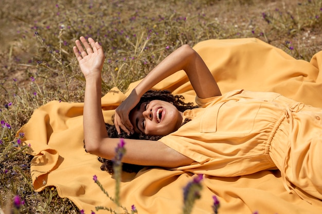 Free photo young woman lying on yellow cloth in nature