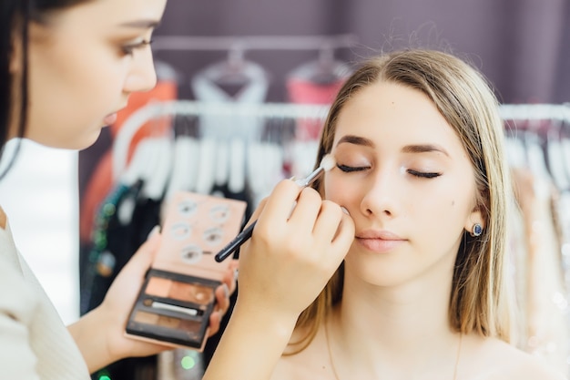 Young woman makes a natural makeup to a model