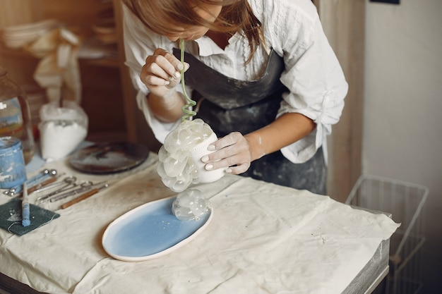 Young woman makes pottery in workshop