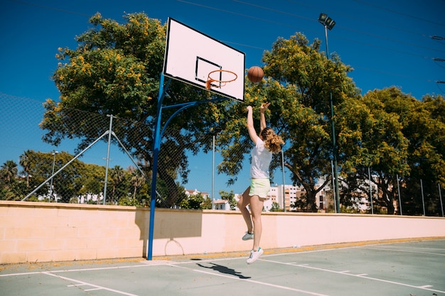 Молодая женщина делает бросок в баскетбол
