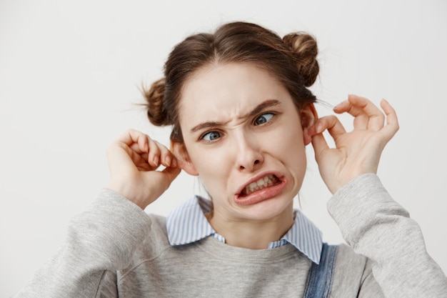 Young woman making goofy face being naughty prankster with twisted mouth. grimacing female actress in casual clothes fooling around squinting eyes. close up