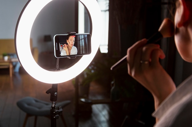 Young woman making a makeup vlog with her smartphone