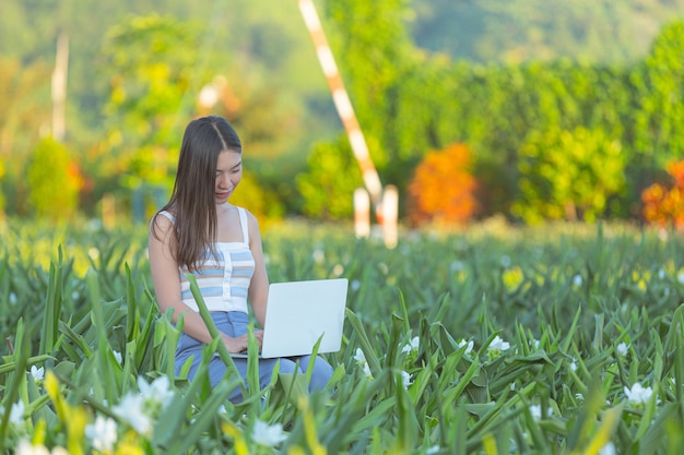 花畑に座ってメモ帳でメモをとる若い女性