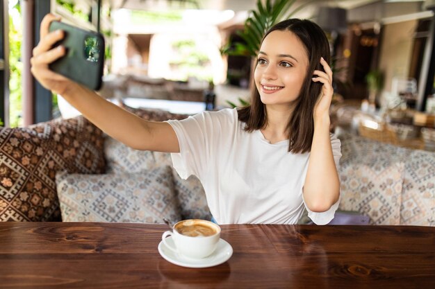 Young woman making a selfie with her smartphone in outdoor cafe