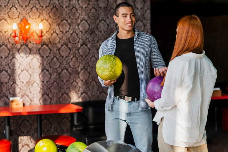 Young woman and man holding colorful bowling balls