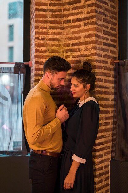 Young woman and man near brick wall and window 