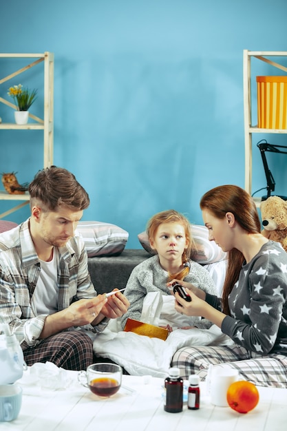 The young woman and man with sick daughter at home. Home Treatment. Fighting with a desease. Medical healthcare. Family iIlness. The winter, influenza, health, pain, parenthood, relationship concept