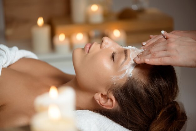 Young woman in mask for face relaxing in spa salon.