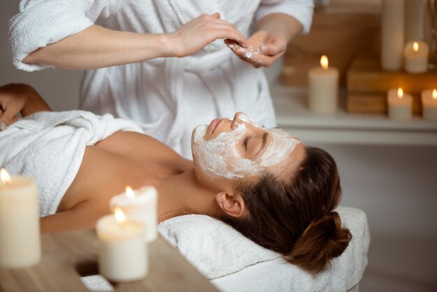 Young woman in mask for face relaxing in spa salon.