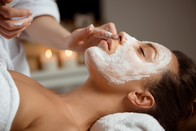 Young woman in mask for face relaxing in spa salon.