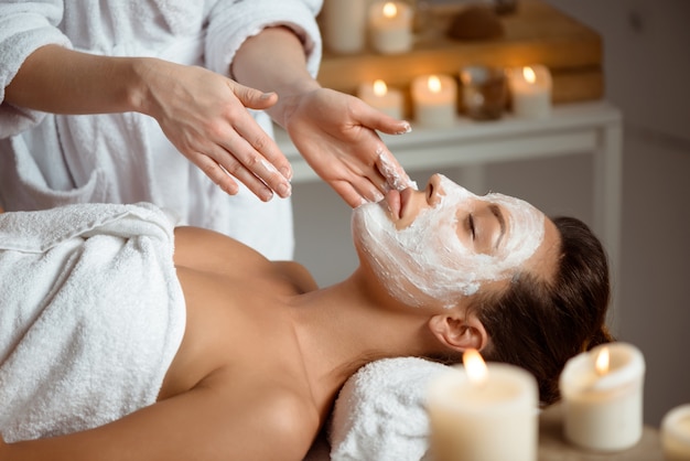 Young woman in mask for face relaxing in spa salon.